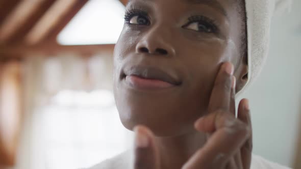 Portrait of african american attractive woman applying face cream in bathroom alt