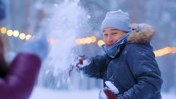Smiling Guy and Girlfriend Play Snowballs on Public Ice Rink