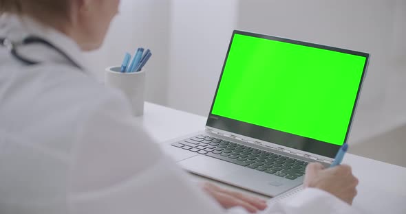 Female Doctor Is Learning Online, Looking at Green Display of Laptop for Chroma Key Technology alt