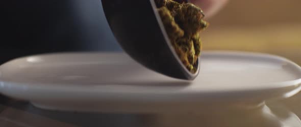 Close up of cannabis buds being spread on a white plate, shallow depth of field alt
