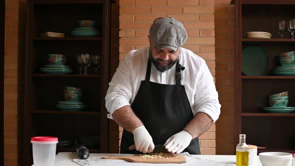 Chef Cuts Garlic with a Knife on a Cutting Board Long Shot