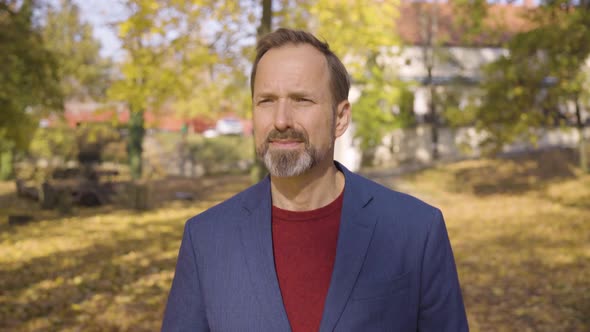 A Middleaged Handsome Caucasian Man Walks and Looks Around in a Park in Fall  Front Closeup