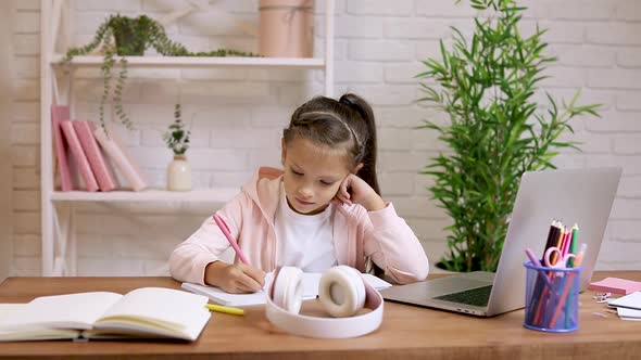 Little Child Girl Using Laptop for Doing School Tasks at Home and Writing Notes