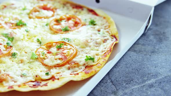 Baked pizza with cherry tomato toppings in delivery box alt