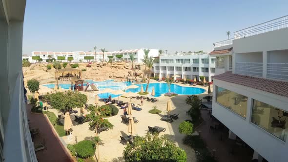 Time Lapse of Hotel Resort with Blue Swimming Pool, Umbrellas and Sunbeds in Egypt alt