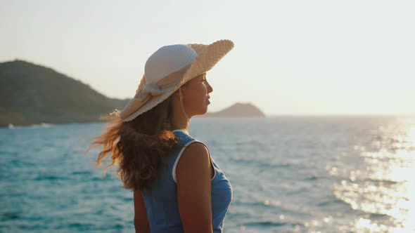 Lady in Summer Dress Standing on Shore at Sunset Admiring Picturesque Seascape alt