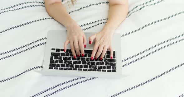 Hands with Red Nail Polish of Young Woman Pressing Laptop Keys