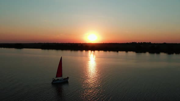 Yacht with scarlet sails at sunset, aerial view