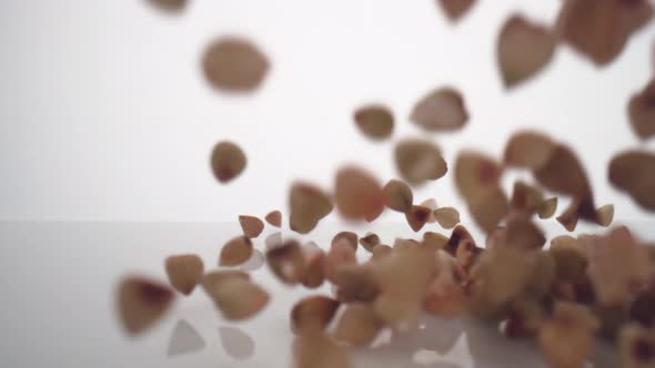Camera follows buckwheat falling and making a heap on surface. Slow Motion. alt