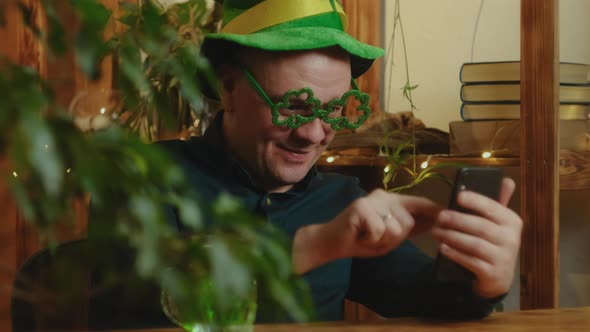 Man Celebrating Saint Patricks Day Using Smartphone at Home alt