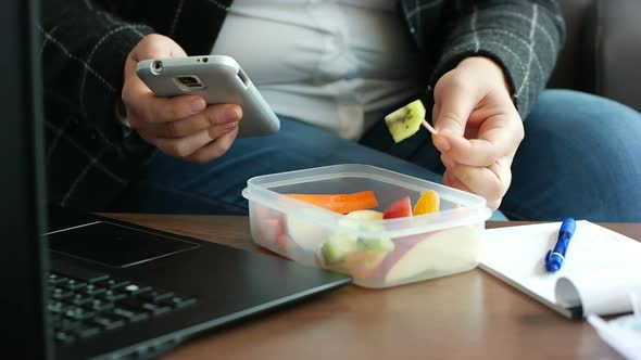 Dieting business woman in suit has eating a healthy fruit snack from lunch box alt