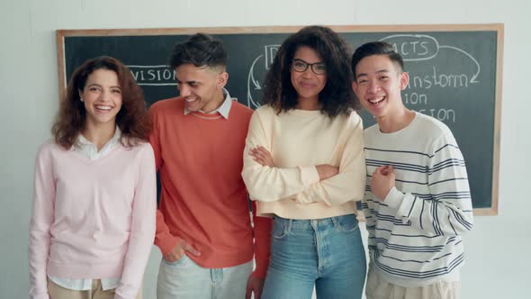 Four Multiracial Happy Students Standing at Black Board in Classroom alt
