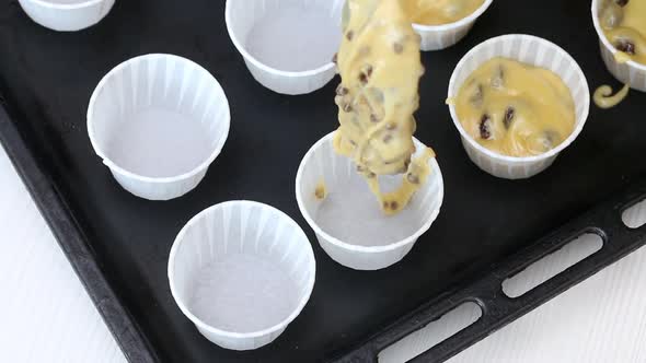 A Woman Puts The Dough Into Muffin Tins On A Baking Sheet. alt