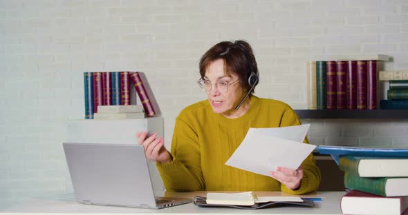 Woman Senior Adult Works in Front of a Laptop Monitor in the Evening Office