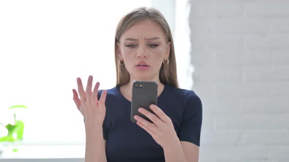 Portrait of Woman Reacting to Loss on Smartphone alt