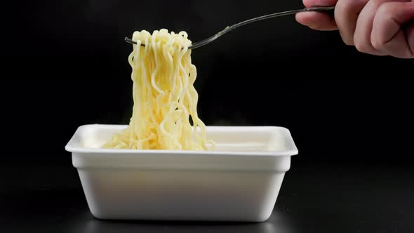 Caucasian Hand with Fork Taking Holding and Putting Back Cooked Instant Noodles