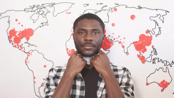 African American Male Takes Off Medical Mask at World Map Background alt