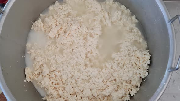 Cheesemaker pour boiling water over fresh cheese to produce mozzarella and caciocavallo alt