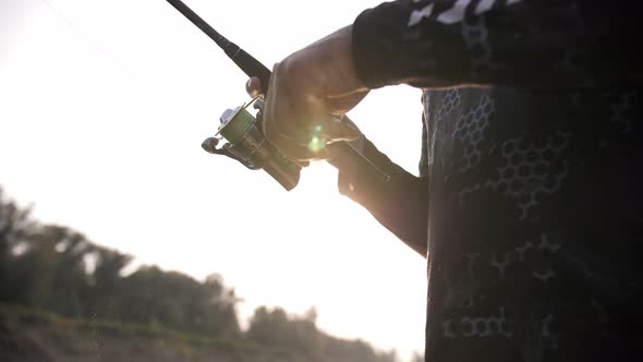 fishing rod in the hands of a fisherman at sunset