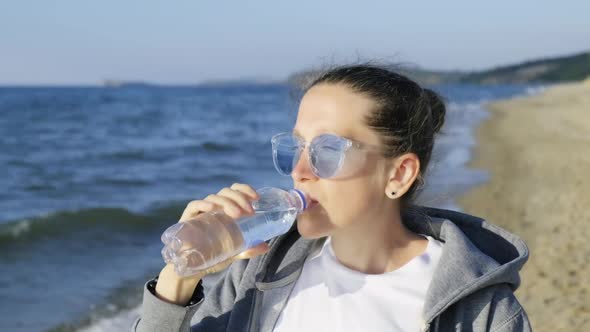 Girl Drinks the Purest Water of Lake Baikal Standing on the Baikal Shore alt