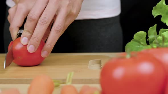Woman's hands using kitchen knife cutting fresh tomato for making healthy sandwich