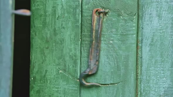 Closeup Slow Motion of a Swinging Door Hook on a Wooden Green Door