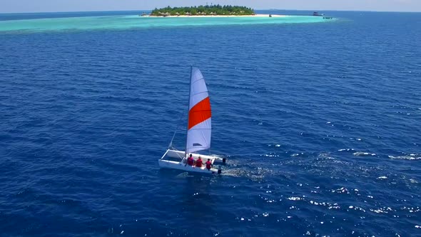 Aerial drone view of a man and woman sailing on a boat to a tropical island. alt