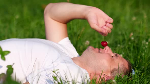 The Guy in the White Tshirt is Resting Lying on the Green Grass alt
