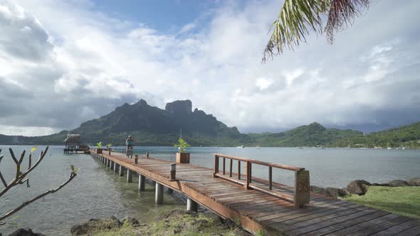 A man riding a bicycle on a dock pier in Bora Bora tropical island. alt