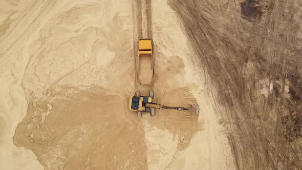 Excavator Loading Sand Into a Truck Body in Sand Quarry alt