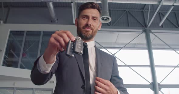 Man in Stylish Suit Holding Keys From New Auto at Salon alt