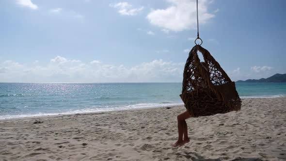 Slow motion of a beautiful young asian woman sitting on swing by the sea