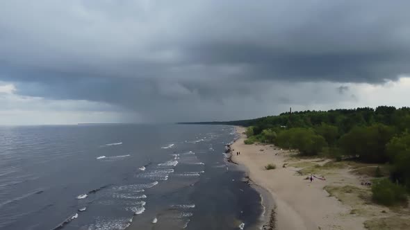 A thundercloud is approaching with rain over the sea. perspective view of coastline from drone.