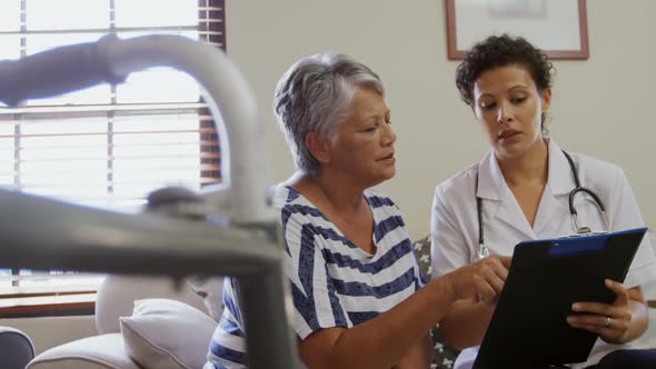 Female doctor interacting with senior woman in living room 4k alt