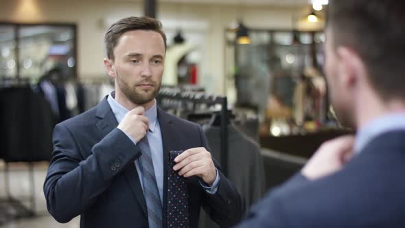 A Close Up Portrait Over the Shoulder of a Dark Haired Business Man Being in a Clothing Shop in alt