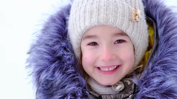 Portrait of a cheerful and happy 5-year-old girl in close-up in winter warm clothes alt