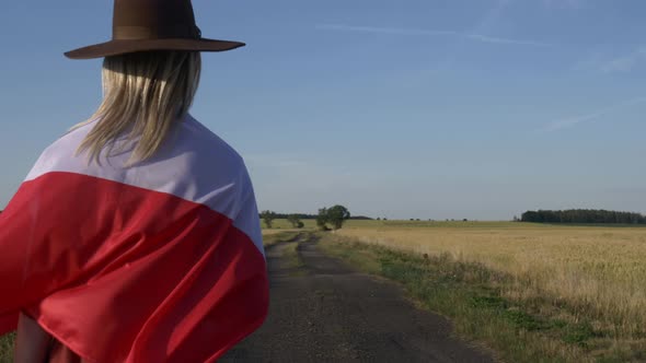 Girl in Poland flag on country road in sunset