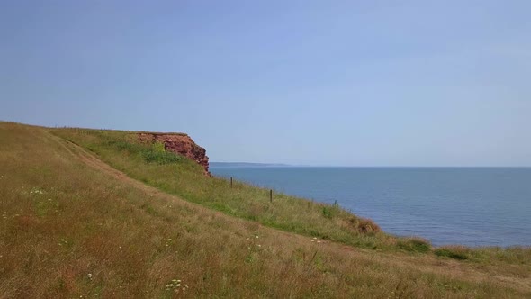 4k Aerial Pull Back away from the ocean along a grassy bluff alt