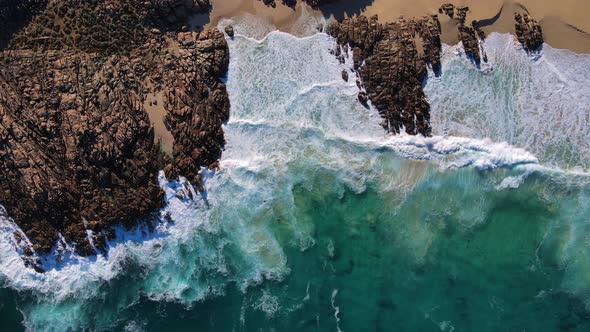 Topdown of beautiful waves breaking over patterned rocks at Injidup beach Western Australia alt