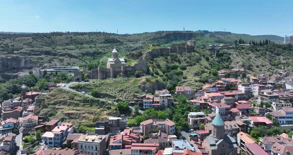 Aerial view of Tbilisi old town buildings and Narikala fortress landmark on hill alt