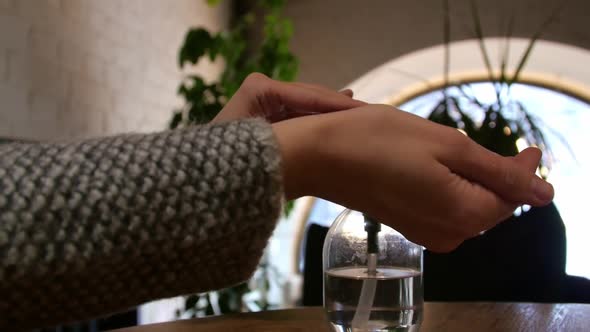 Young Woman Hands Applying Sanitizer in Cafe