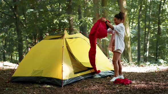 Young Positive African American Lady Putting Sleeping Bag Into Tent Preparing for Overnight Stay in alt