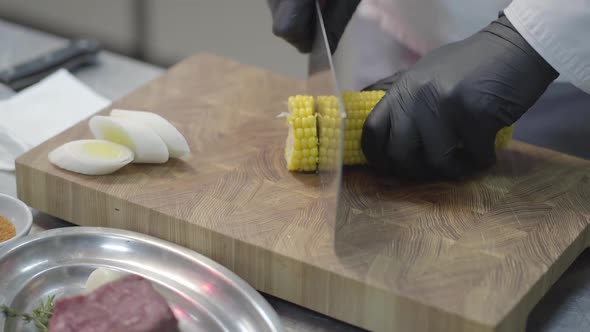 Close-up Hands of a Professional Unrecognized Shuf in Black Gloves Are Chopping Corn Into Round alt