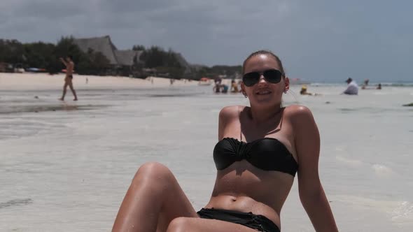 Young Woman in Black Bikini Tans on a Paradise White Sandy Beach Lies By Ocean alt
