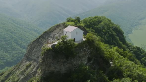 Arc shot of wild forest surrounding a medieval, secluded church nearby Tsveri. alt