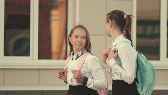 Girlfriends Go To School. School Girls with Backpacks Go To School on Street. They Have a Lot of Fun alt