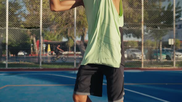 Closeup of Young Spotsman Bouncing Basketball Ball Training on Ground Floor of the Court alt