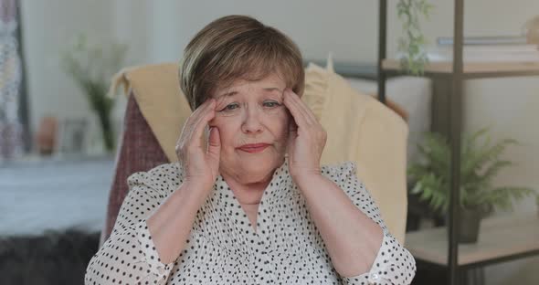Elderly Pensioner Having Headache and Massaging Temples, Woman in 70s in Looking Tired and Rubbing alt