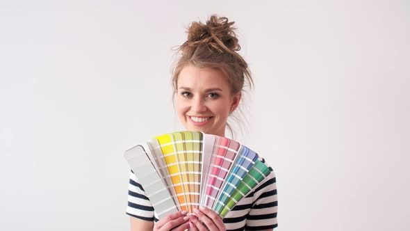Portrait of smiling woman showing paint swatches  alt