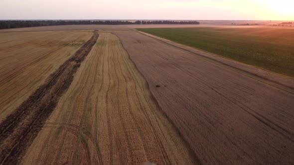 Tilting camera up and flying forward over the combine harvester loading grain to the car